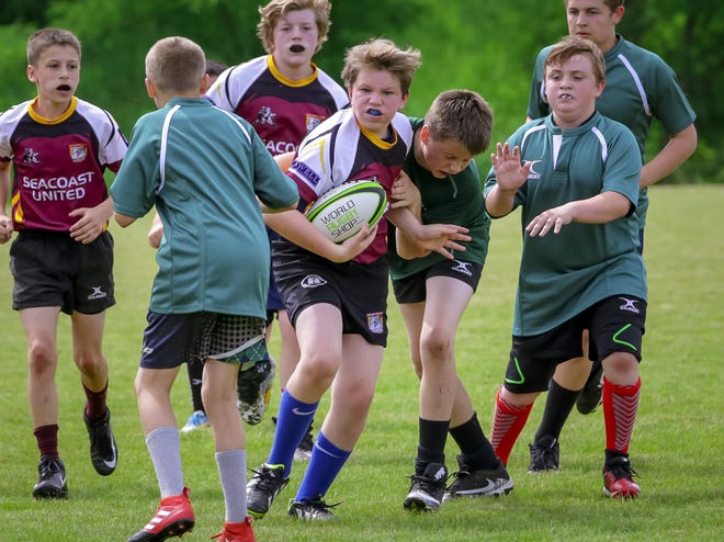 Jamie Dunne, center, a 12-year-old from Kennebunk, Maine, carries the ball for the Essex Bulldogs during New Hampshire Youth Rugby action Saturday morning in Dover. [Shawn St. Hilaire/Fosters.com]