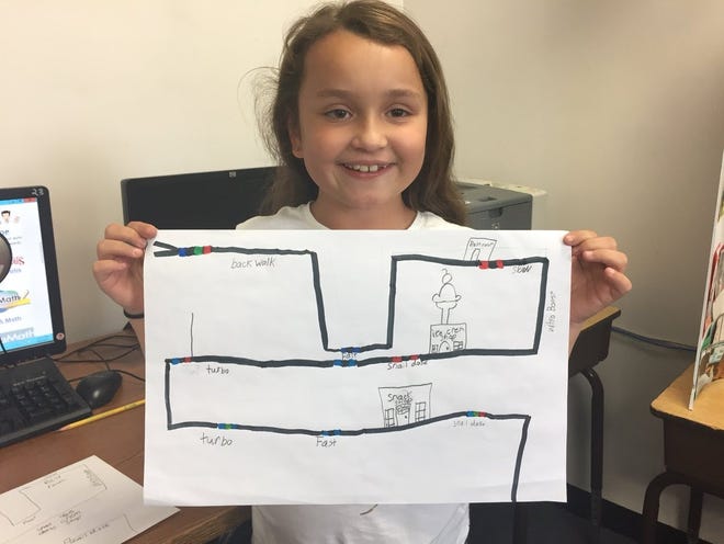 Olivia Swanson, a third-grader at Jefferson Elementary School, explains how her bot will slow down to “snail dose” at the snack shop and perform a “backwalk” as it leaves the virtual town she has created using Ozobots. [Courtesy Photo / Rachel Mack]
