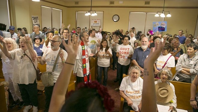 Martha Mercado raises her arms in leading a song with protesters who packed the Williamson County Courthouse to oppose the T. Don Hutto detention center in Taylor. RALPH BARRERA / AMERICAN-STATESMAN