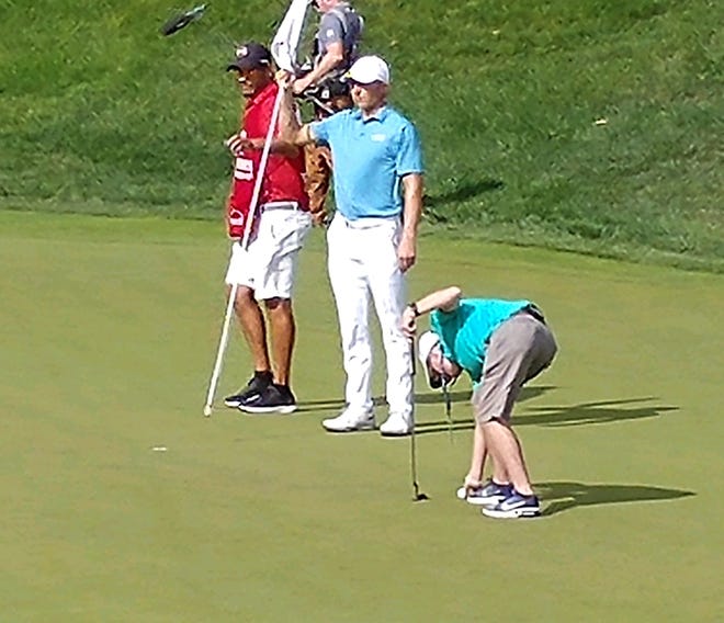Grayson Beck gets a putt lined up as Jordan Spieth holds the flag stick on the 18th green during the Travelers Championship pro-am last Wednesday in Cromwell, Conn. [PGA Tour photo]