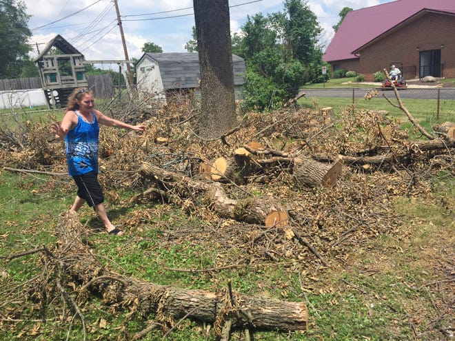 PHIL LUCIANO/JOURNAL STAR Robin Irvin strolls through a mess of limbs and logs left at her Peoria home after two trees were trimmed by Ameren Illinois. In light of what the utility calls a "miscommunication" between Irvin and the tree crew, Ameren has decided to clean up the debris.