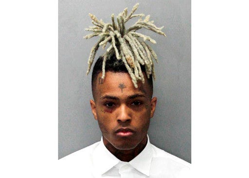 This undated mugshot released by the Miami- Dade Corrections & Rehabilitation Department shows rapper XXXTentacion. Following his death on June 18, 2018, XXXTentacion has topped the Billboard Hot 100 chart with “Sad!” and his two albums have landed in the Top 10. (Miami- Dade Corrections & Rehabilitation Department via AP)