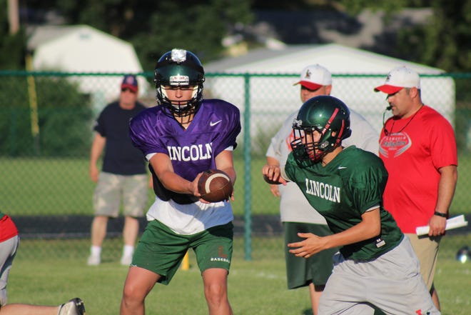 Dreyden Pozsgai, left, hands the ball off to Nathan Garriott, right, during a recent football practice that was open to the public. [Photo by Jean Ann Miller/The Courier]