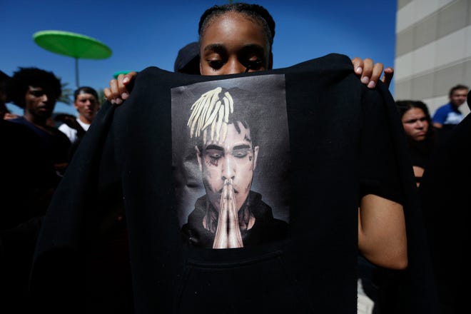 Anneyah Lawson, 14, of St. Petersburg holds up a sweatshirt with an image of slain rapper XXXTentacion, before his memorial on Wednesday in Sunrise. The rapper was gunned down in a luxury sports car last week. [AP Photo/Brynn Anderson]