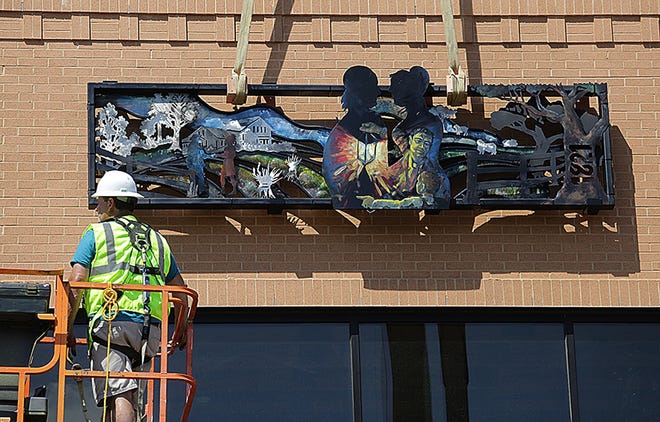 Matt Frantz, of Frantz Brothers Construction, puts the final touches on one of the seven steel sculptures that were installed Friday on the First North Building in downtown Massillon. Theme of the sculptures is Massillon history. (IndeOnline.com / Kevin Whitlock)