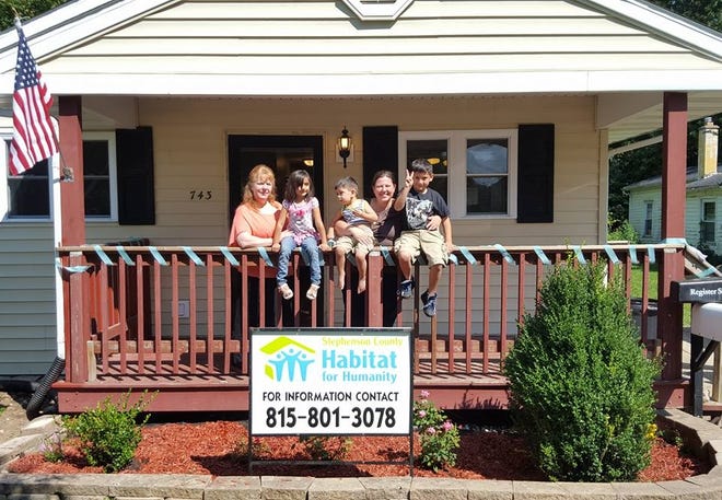 Tracyann Reynolds, left, executive director of Stephenson County Habitat for Humanity, poses with a family in front of their new home in August. [PHOTO PROVIDED]
