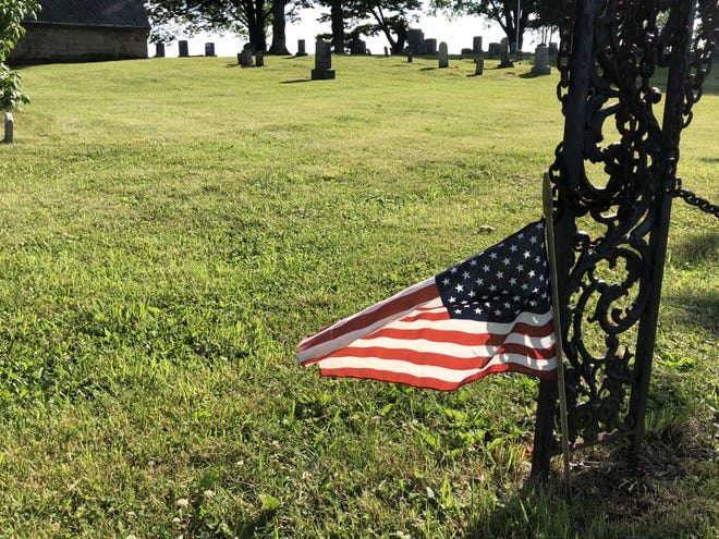 American flags are missing from the graves of veterans at South Farmington Cemetery, although this one at the entrance is still flying. [MIKE MURPHY/MESSENGER POST MEDIA]