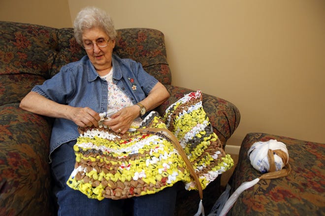 Pat Thompson crochets strips of plastic bags together in to a mat about 2.5 feet across and 6 feet long in her home Monday, June 25, 2018. Thompson has made 105 of the mats, which are distributed to homeless people for them to sleep on. [Travis Morisse/HutchNews]