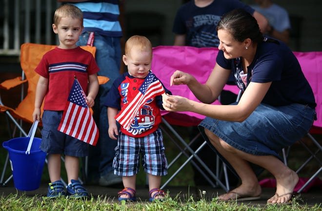 Janalee Brubaker helps Brayden Davidson, 2. and Bradley Brubaker, 15 months, get ready for the Lattimore Fourth of July parade last year. [Brittany Randolph/The Star]