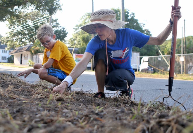 Colleen Holdcraft pulls weeds with her son, 10-year-old Jonas. About 30 volunteers worked to beautify the outside of the Gulf Coast Children's Advocacy Center's new Trauma Therapy Office on Saturday morning. [PATTI BLAKE/THE NEWS HERALD]