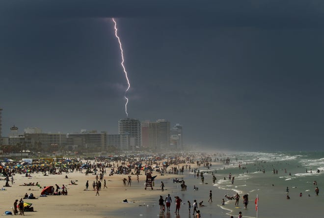 In this July 2016 photo, beachgoers get an early fireworks show as lightning strikes north of Daytona Beach during a brief thunderstorm. [Nigel Cook/GateHouse Media Services/File]