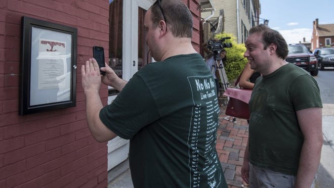 Brandon Hintze, left, of Alexandria, Va., and Brian Tayback, of Shrewsbury, Pa., take a photo of the menu outside of the Red Hen Restaurant on June 23 in Lexington, Va.