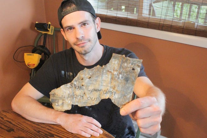 Tyler Shorb shows a piece of a metal newspaper template for The Record Herald from Feb. 6, 1973, that he found while metal detecting. JOHN IRWIN/ THE RECORD HERALD