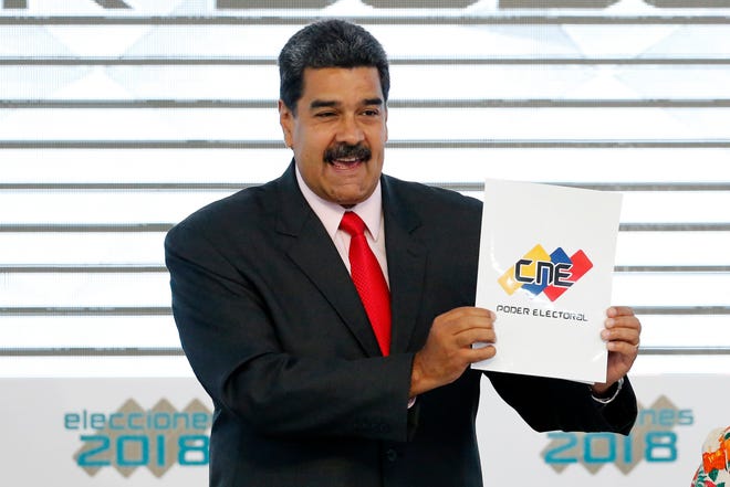 FILE - In this May 22, 2018, file photo, Venezuela's President Nicolas Maduro holds up the National Electoral Council certificate declaring him the winner of the presidential election, during a ceremony at CNE headquarters in Caracas, Venezuela. As a meeting last August in the Oval Office to discuss sanctions on Venezuela was concluding, President Donald Trump turned to his top aides and asked an unsettling question: With a fast unraveling Venezuela threatening regional security, why can’t the U.S. just simply invade the troubled country? (AP Photo/Ariana Cubillos, File)