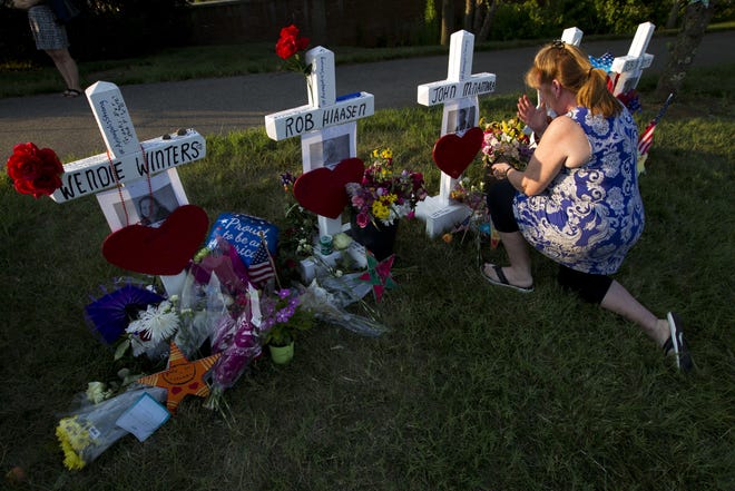 Colleen Joseph prays over the crosses at a makeshift memorial at the scene outside the office building housing The Capital Gazette newspaper in Annapolis, Md., on Sunday. [Jose Luis Magana/AP]
