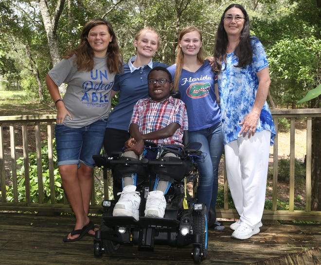 Alyssa, Hailey, David and Kaitlen pose with their adopted mother, Joanne Uszuko, for a family photo on Tuesday. [PATTI BLAKE/THE NEWS HERALD]