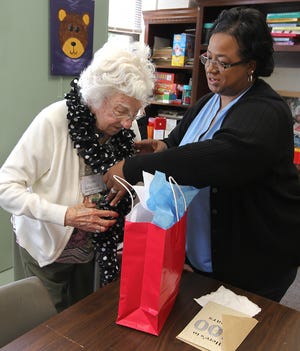 Chenita Floyd assists Hazen Rabenhorst with a handmade scarf that she received for her 100th birthday. The Center-Day Care Services for Adults held a cookout and celebration for Rabenhorst who will turn 100 on July 7. [JOHN CLARK/THE GASTON GAZETTE]