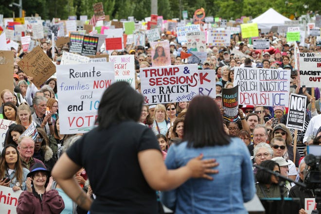 Monserrat Padilla, left, puts her arm around Aurora, an undocumented immigrant, as Aurora speaks to several thousand demonstrators gathered outside the Federal Detention Center in SeaTac to protest the separation of families crossing the U.S.-Mexico border and President Donald Trump's immigration policies as part of a rally for Families Belong Together on June 30 in Seattle. [Genna Martin /seattlepi.com via AP]