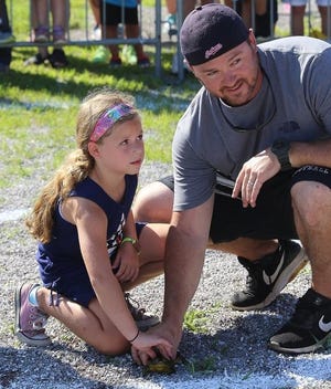 Ella Range, with her dad Ryan Range, of New Philadelphia wait for the start of their heat during the frog-jumping contest Wednesday at the First Town Days Family Day. (TimesReporter.com / Jim Cummings)