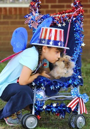 Lucy Merritt, 7, of New Philadelphia, gives her lion head bunny Sock a kiss before the start of the Pet Parade during the Gnadenhutten Fireworks Festival Friday at Heck's Grove Park in Gnadenhutten. The Festival continues today, starting with a car show and a basketball tournament at 9 a.m. and the grand parade at 2. The day closes with the Country Festival in the Sky fireworks display, scheduled for 10 p.m.(TimesReporter.com / Pat Burk)