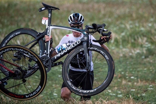 Britain's Chris Froome carries his bicycle after falling into a ditch when crashing with other riders during the first stage of the Tour de France on Saturday. Froome recovered to finish the stage 51 seconds behind stage winner Fernando Gaviria of Colombia. [Jeff Pachoud, pool photo via AP]