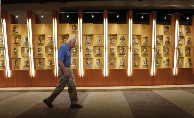 Volunteer Coulter Schmitt walks past part of the Wall of Fame in the World Golf Village Hall of Fame and Museum while making his rounds through the exhibits. [BOB SELF/GATEHOUSE FLORIDA]