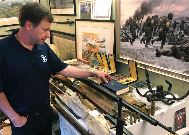 In this June 22, 2018 photo, filmmaker Tim Gray looks at books, medals and other items from World War II, some of the numerous items destined for a planned WWII education center in Wakefield, R.I. Gray, founder of the nonprofit World War II Foundation, plans to open the center in September. (AP Photo/Jennifer McDermott)