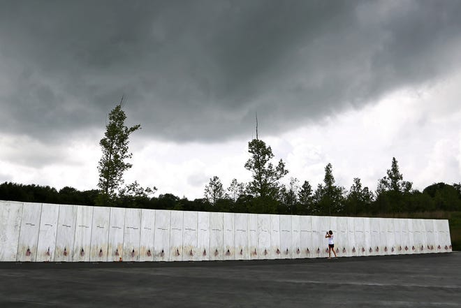 In this May 31, 2018 file photo, a visitor to the Flight 93 National Memorial pauses at the Wall of Names honoring 40 passengers and crew members of United Flight 93 killed when the hijacked jet crashed at the site during the 9/11 terrorist attacks, near Shanksville, Pa. Four shipping containers holding the remaining wreckage of United Flight 93 were buried near the Wall of Names in a private ceremony on June 21, 2018, the Flight 93 National Memorial said Monday, July 9, 2018. The wreckage is buried in a restricted access zone in the woods beyond the Wall of Names marked by a giant boulder, not accessible to the public or media. [AP Photo/Gene J. Puskar, File]