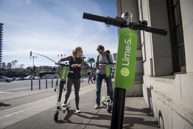 People use a smartphone to LimeBike shared electric scooters on the Embarcadero in San Francisco. MUST CREDIT: Bloomberg photo by David Paul Morris.