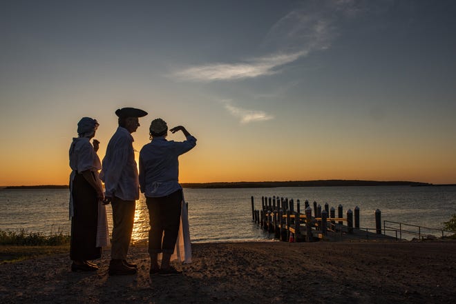 Portsmouth Historical Society members Nanci Smith and Richard and Gloria Schmidt, dressed in period attire, wait to greet kayakers Monday night at Weaver Cove in Portsmouth. [DAVE HANSEN/STAFF PHOTOGRAPHER]