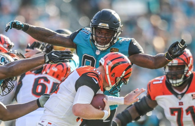 Jaguars defensive end Yannick Ngakoue (91) wraps his arms around Cincinnati Bengals quarterback Andy Dalton (14) during a game Nov. 5 in Jacksonville. [For The Florida Times-Union/Gary Lloyd McCullough]