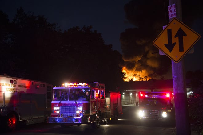 Firefighters respond to a fire at an auto salvage junkyard in the Kensington neighborhood of Philadelphia, Tuesday, July 10, 2018. (Joe Lamberti/Camden Courier-Post via AP)