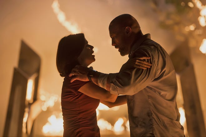 Neve Campbell, left, and Dwayne Johnson in a scene from "Skyscraper." [Kimberley French/Universal Pictures via AP]