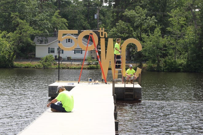 Workers at Mirror Lake Beach in Pemberton Township prepare a 50th anniversary sign for the Water Carnival. [KELLY KULTYS / STAFF PHOTOJOURNALIST]