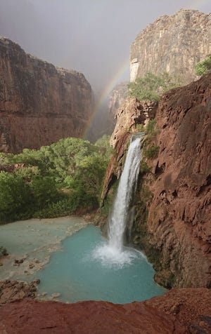 This Wednesday, July 11, 2018 photo released by Benji Xie shows a rainbow over a waterfall on the Havasupai reservation in Supai, Ariz. About 200 tourists were being evacuated Thursday from a campground on tribal land near famous waterfalls deep in a gorge off the Grand Canyon. (Benji Xie via AP)
