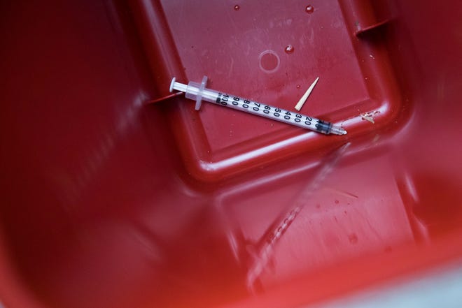 In this Tuesday, July 3, 2018, photo, a used syringe removed from the bed of a sidewalk tree near VOCAL-NY headquarters in the Brooklyn borough of New York is seen in a disposal container. VOCAL-NY runs a needle exchange and harm reduction services, as well as overdose prevention and other services for people who use drugs. (AP Photo/Mary Altaffer)
