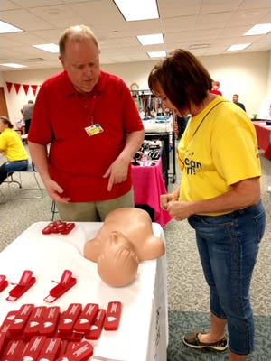 Steve Baldridge of Samaritan Hospital gives Jane Stoodt a refresher course in CPR using a CPR dummy during the Mohican Area Community Fund Agency Fair Saturday.