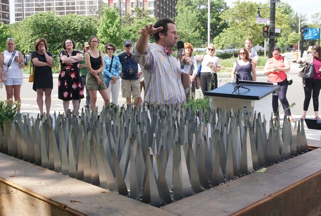 Yarrow Thorne, founder and executive director of the Avenue Concept, a Providence-based nonprofit, discusses George Sherwood's kinetic piece "Grey Matter" during the unveiling of multiple public art installations downtown on Friday. [The Providence Journal / Sandor Bodo]