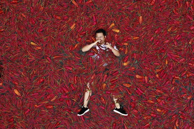 In this July 8 photo, a contestant lays on a pool of red chilies as he takes part in a chili eating competition in Ningxiang in China's central Hunan province. (Chinatopix via AP)