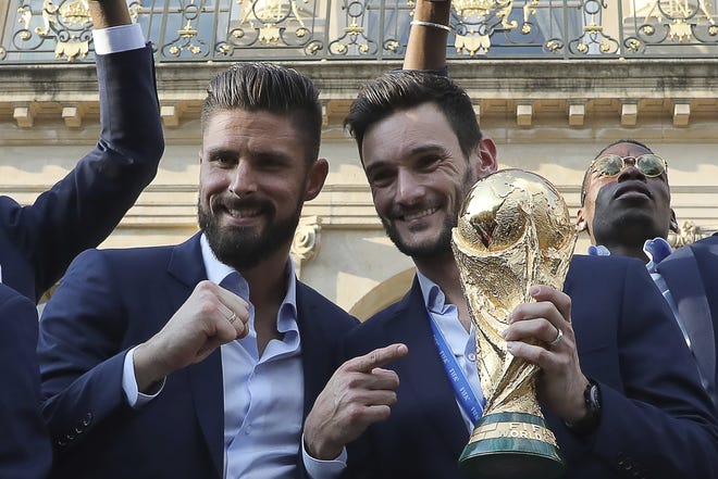 Olivier Giroud, left, and Hugo Lloris of the French national team show off the World Cup trophy during Monday's celebration in Paris. [Ludovic Marin/Pool Photo via AP]