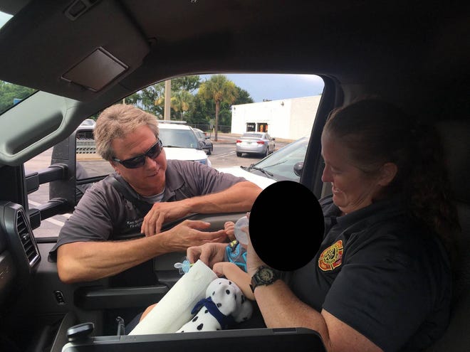 Rescue personnel care for a baby boy left in the back seat of a vehicle Tuesday afternoon in the parking lot of Cosmo Prof at 2403 Enterprise Road near Orange City. [Orange City Fire Department]