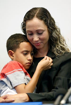 A Brazilian mother, who asked to be identified only as W.R. holds her 9-year-old son A.R. during a news conference at the Brazilian Worker Center on Monday in Boston. The mother spoke to reporters Monday after she was reunited with her son Saturday at Boston's Logan airport. They had been separated since May 30 under the Trump administration's zero-tolerance immigration policy. [Michael Dwyer/The Associated Press]