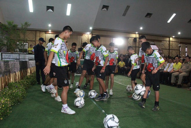 In this July 18, 2018, photo provided by Chiang Rai Public Relations Department, members of the rescued soccer team show their skills before a press conference regarding their experience being trapped in the cave in Chiang Rai, northern Thailand. The Thai soccer boys and their coach began their first day back home with their families since they were rescued from a flooded cave with a trip to a Buddhist temple on Thursday, July 19, to pray for protection from misfortunes. (Chiang Rai Public Relations Department via AP)