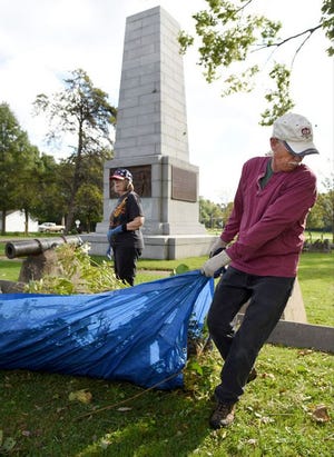 Volunteers Karin Ciaccio and David Keenan Miles (top, right) work to clear brush from the river view of the Campbell's Island monument in 2016. The monument commemorates a battle between U.S. soldiers and American Indians during the War of 1812.