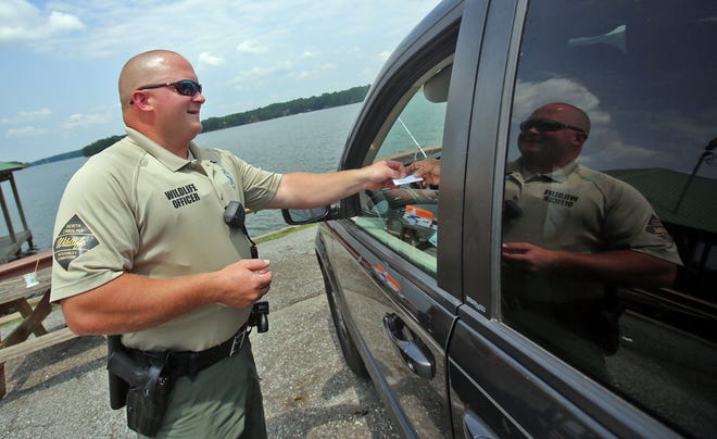 Issac Hannah checks fishing licenses at Moss Lake during his shift. [Brittany Randolph/The Star]