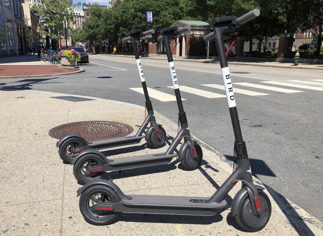 Three dockless scooters stand on a sidewalk across the street from a Johnson & Wales University campus on Friday in downtown Providence, R.I.  [AP Photo]