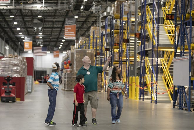 Bob Pedato, center, an inbound shipping employee at AutoZone's distribution center in Ocala, shows his family around the warehouse where he works Saturday. Dignitaries, employees and their family attended the grand opening of the AutoZone distribution center, at 3321 NW 35th Ave. [Doug Engle/Staff photographer]