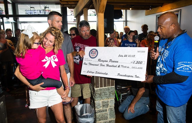 Kim Pearce looks at her daughter Reagan as she and her husband, Chatham Police Sgt. Ryan Pearce, are presented with a check by Mylas Copeland on behalf of The Peacekeepers, a not-for-profit organization created to assist the men and women of law enforcement and military in Illinois, during a stop on the 2018 Peacekeepers Ride at The Creek Pub & Grill in Chatham Sunday, July 22, 2018. The check was in support of the family after their daughter Karly died in a sledding accident in January. [Ted Schurter/The State Journal-Register]