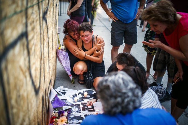 Desirae Shapiro, 19, next to wall kneeling at right, and her mother, Gina Shapiro, friends of 18-year-old Danforth shooting victim Reese Fallon, mourn while visiting a makeshift memorial, Monday in Toronto, remembering the victims of the shooting on Sunday. [MARK BLINCH/THE CANADIAN PRESS/ASSOCIATED PRESS]