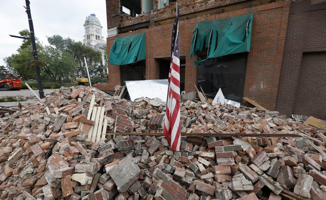 A flag sits in rubble in front of tornado damaged building on Main Street Friday in Marshalltown. Several buildings were damaged Thursday evening by a tornado in the main business district in town including the historic courthouse. [Charlie Neibergall/The Associated Press]